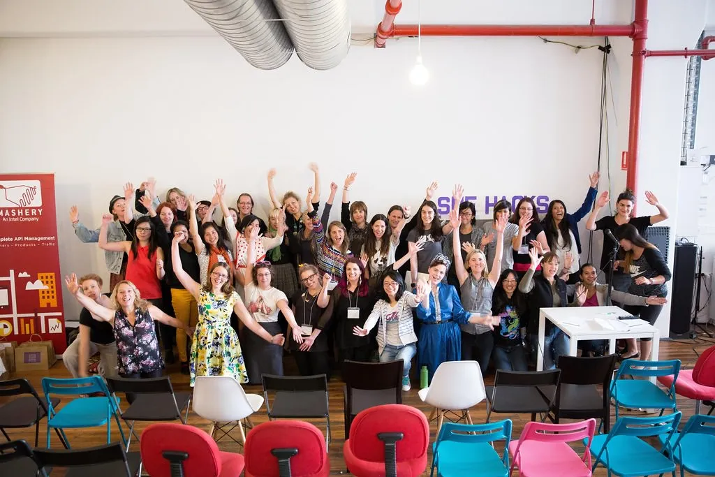 A big group of girl geeks with their hands in the air