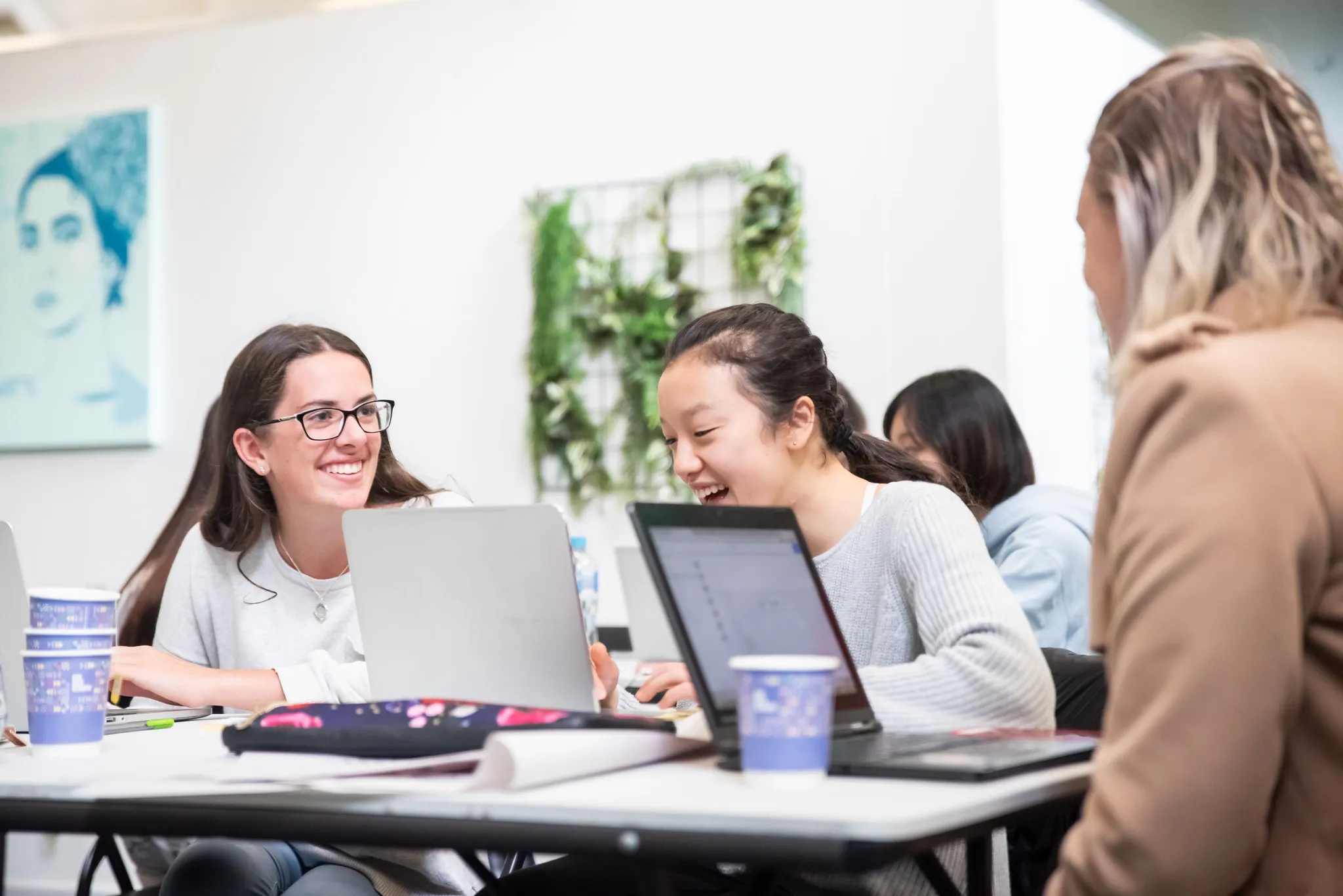Women at laptops in a bright room