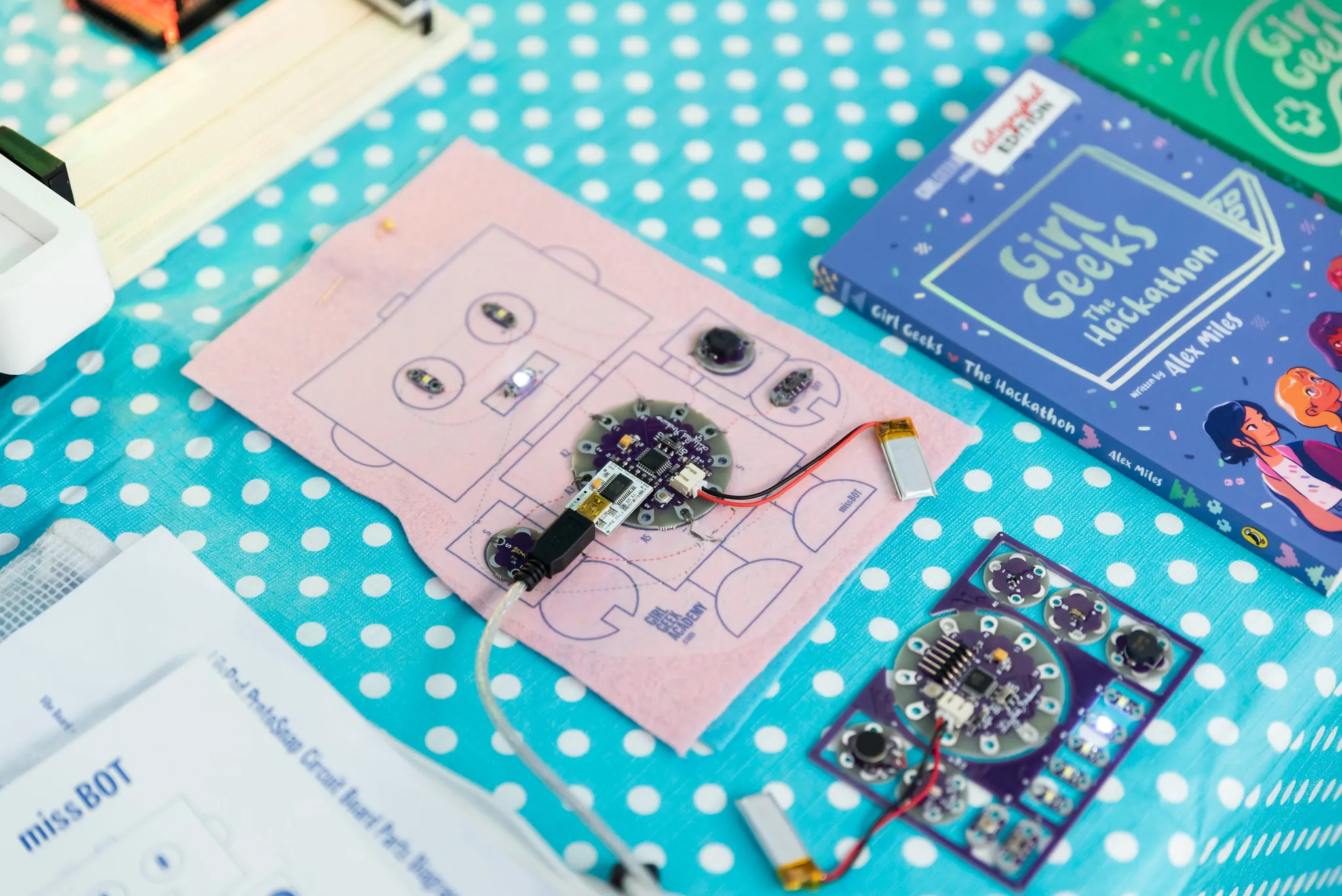 Circuit boards and a Girl Geeks book on a spotty tablecloth