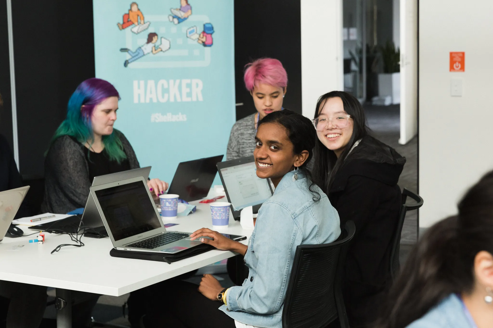 Participants at laptops in front of the Hacker banner