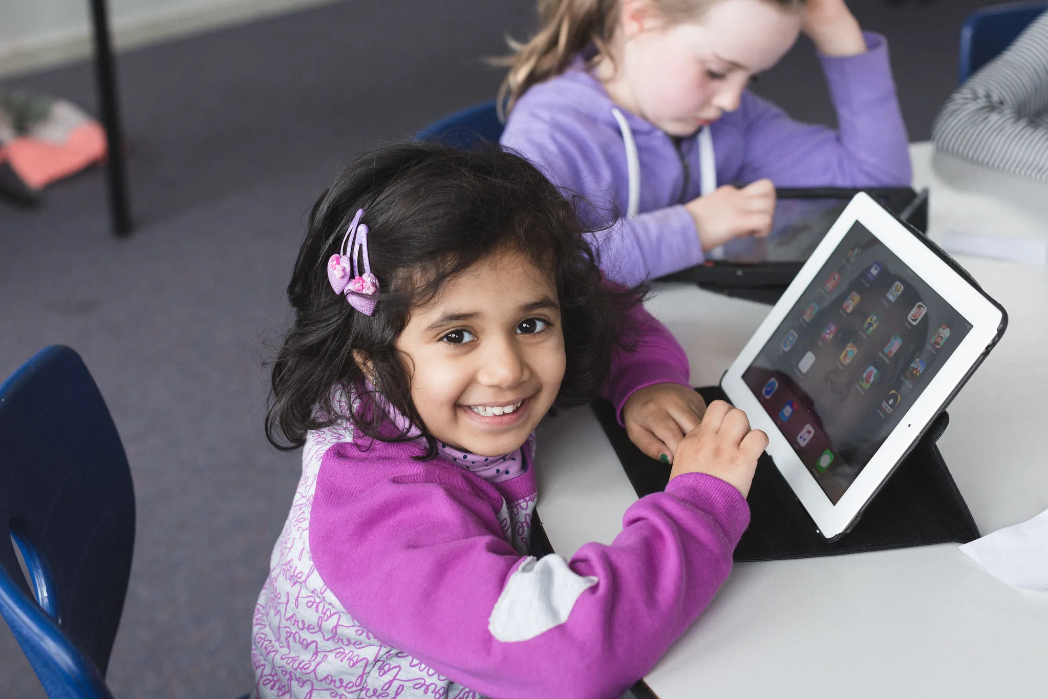 A young girl smiling while coding on an iPad