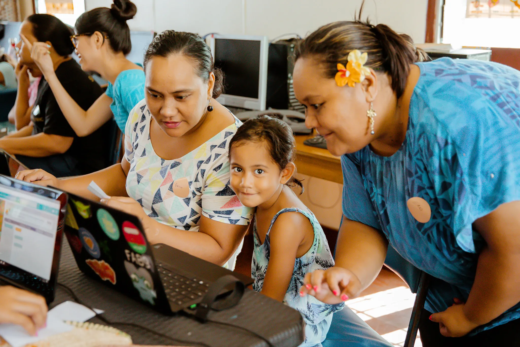 Women and girls coding together on a laptop
