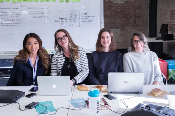 Four women at a table with laptops