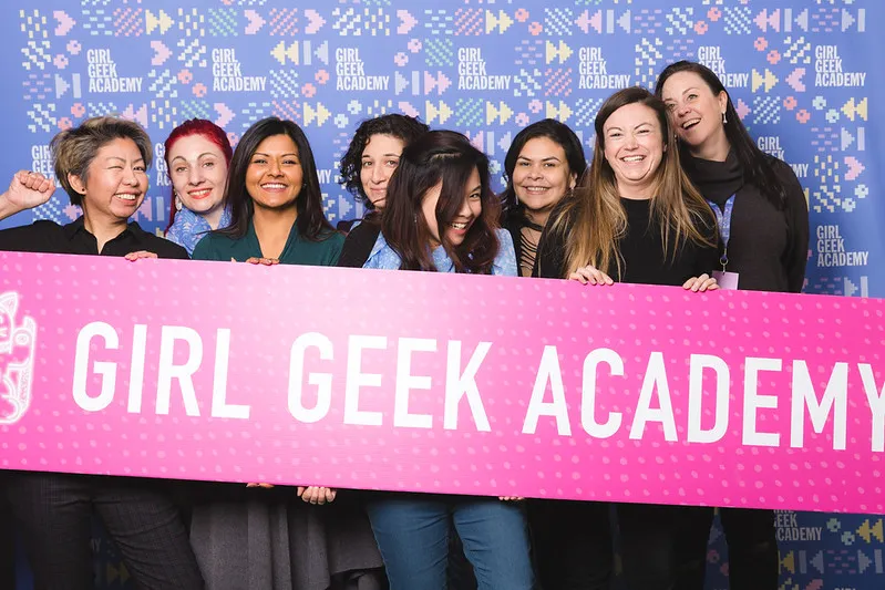 The Girl Geek Academy crew holding a big pink Girl Geek Academy banner