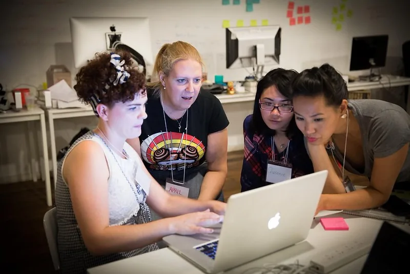 Four women laughing together over a laptop at #SheHacks 2014