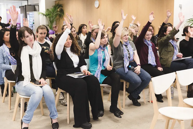 A room of participants with their hands in the air at #SheHacks 2016