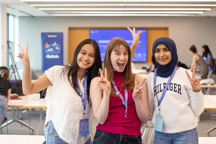 Three students posing and waving