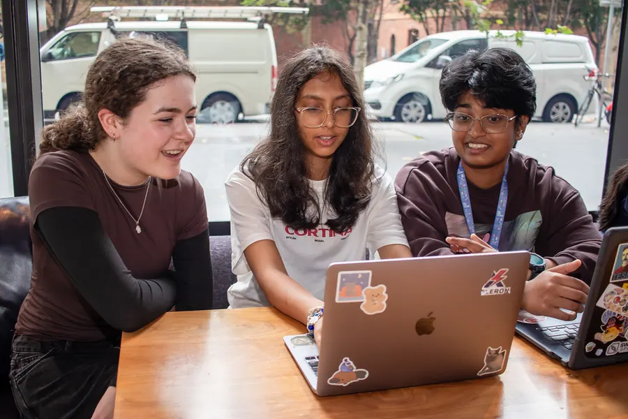 Two students laughing as they look at an app on a laptop