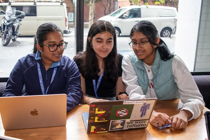 Three students working on laptops at a table