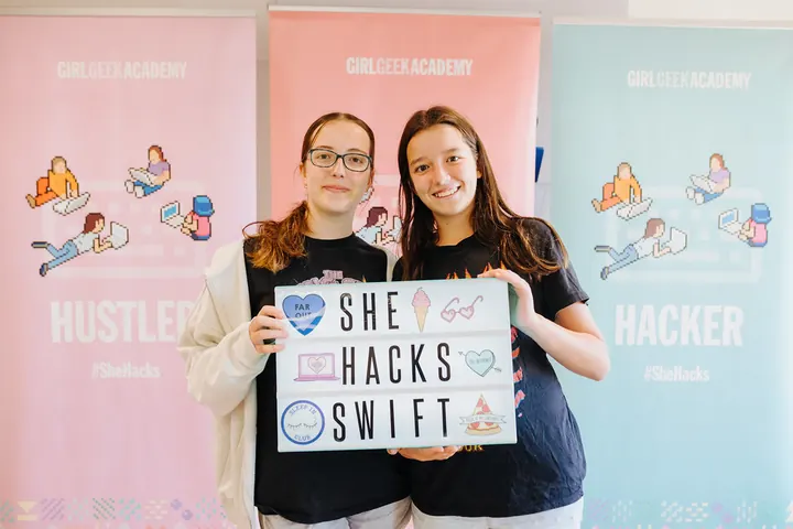 Two students holding a SheHacksSwift sign